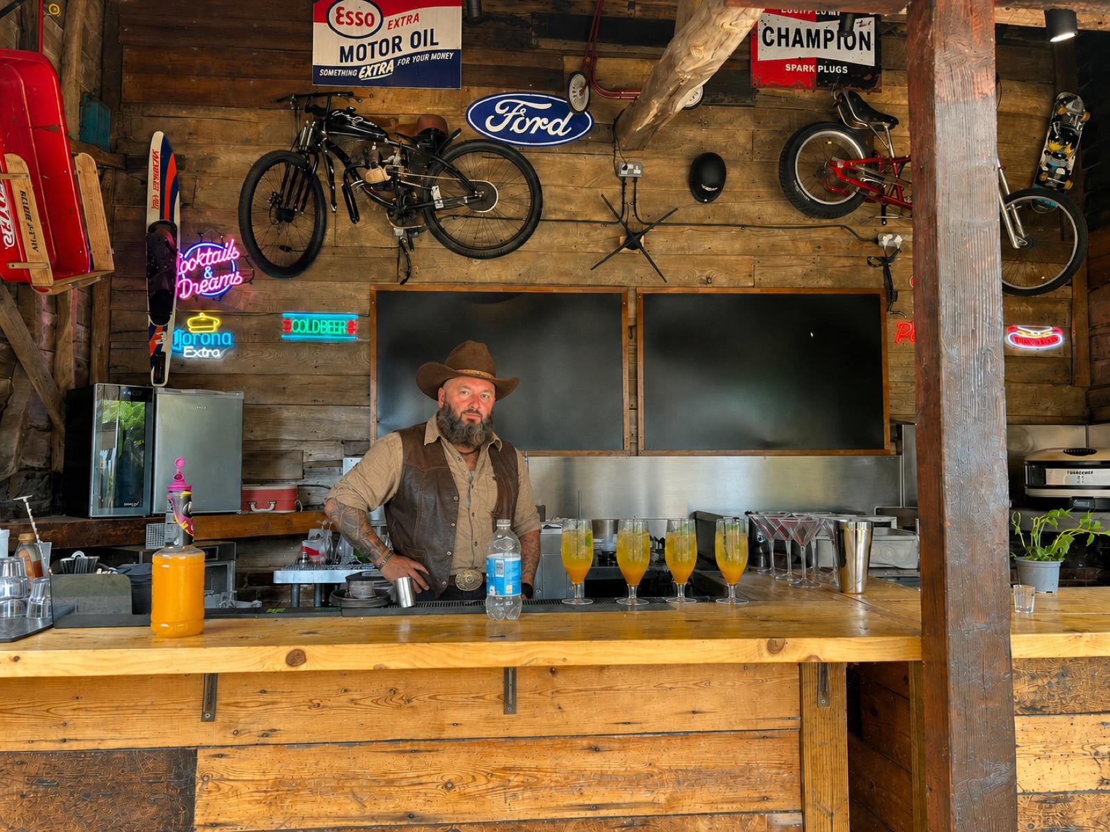 Brian's Bar at Flint Hall — the barman behind the rustic open-air bar with cocktails and neon signs